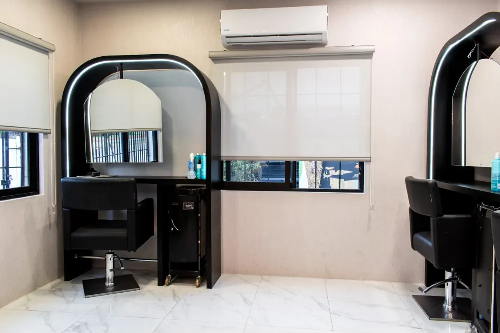 Salón de belleza con espejos en arco iluminados y piso de mármol, proyecto de F&A