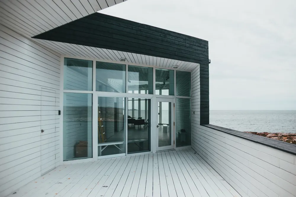 Terraza de madera con puertas de vidrio frente al mar