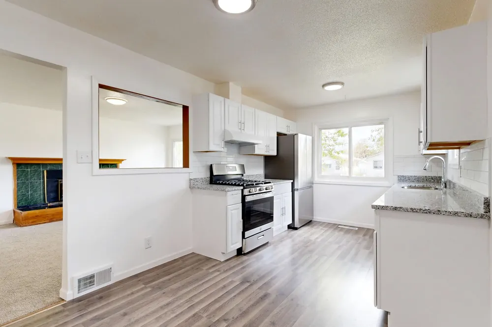 Cocina remodelada con muebles blancos y piso de madera